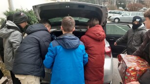 uczniowie pakują dary do bagażnika samochodu