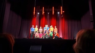 uczniowie w kolorowych koszulkach stoją na scenie