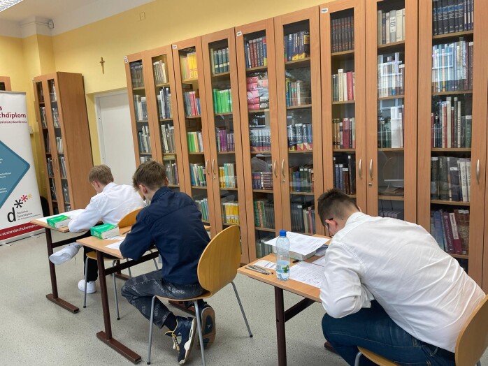 uczniowie piszą egzamin pisemy DSD w czytelni szkoły