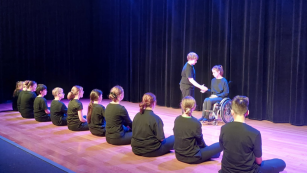 aktorzy - uczniowie siedzą na scenie podczas przedstawienia
