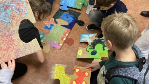 uczniowie rozkładają swoje puzzle na podłodze