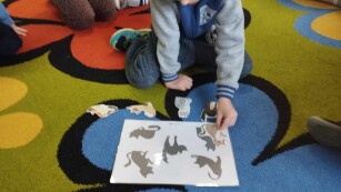 chłopiec wykonuje układankę na dywanie