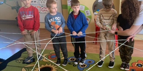 chłopcy trzymają rozciągniętą włóczkę tworząc sieć