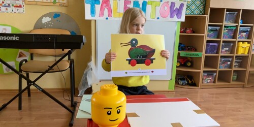 chłopiec pokazuje rysunek drewnianej kaczki, którą stworzył twórca Lego