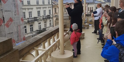 uczniowie słuchają hejnał miasta na balkonie Ratusza