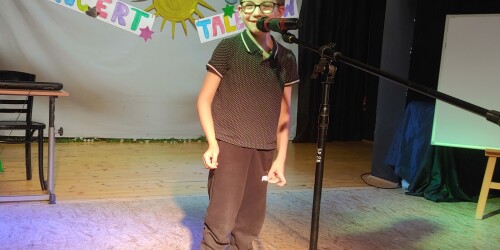 chłopiec stoi przed mikrofonem i recytuje wiersz