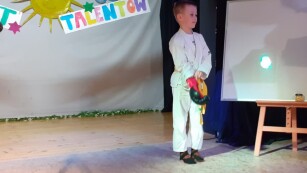 na scenie stoi chłopiec w stroju karate