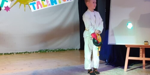na scenie stoi chłopiec w stroju karate
