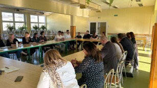 uczestnicy debaty zgromadzeni przy stole w jadalni szkolnej